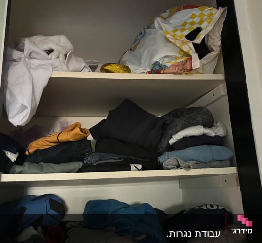 ארון בגדים עם בגדים מקופלים ומפוזרים